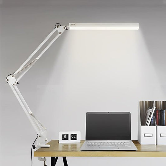 Lampe de bureau articulée noire avec abat-jour lumineux posée sur un bureau en bois, décor minimaliste avec plante verte.