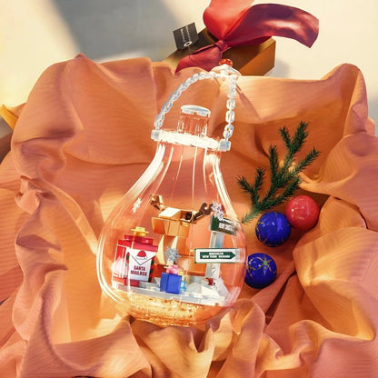 Boule de Noël lumineuse féerique posée sur tissu rose avec cadeaux