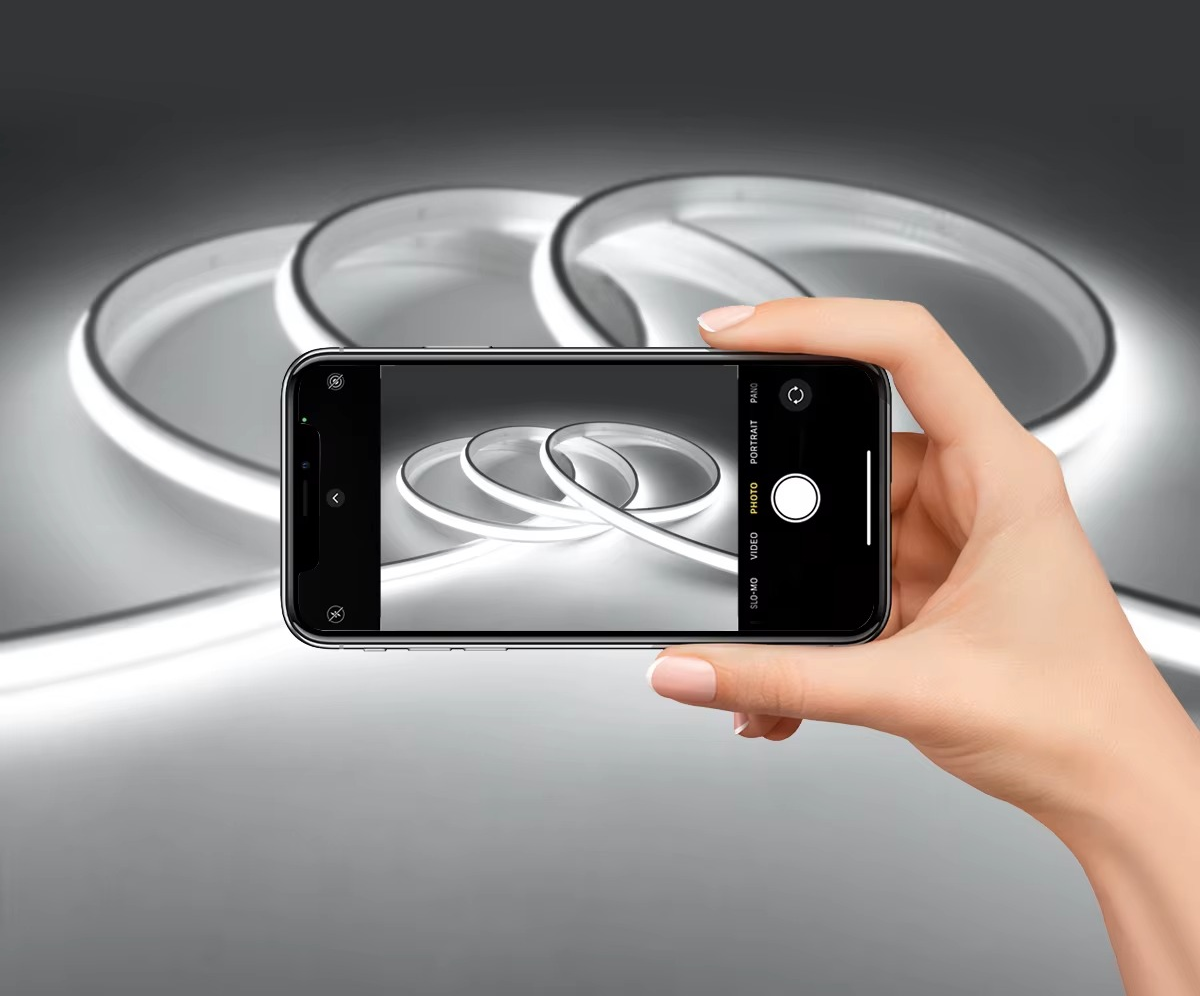 Main tenant un smartphone photographiant des rouleaux de bande LED COB blanc froid — Mon Univers - Mes Lumières