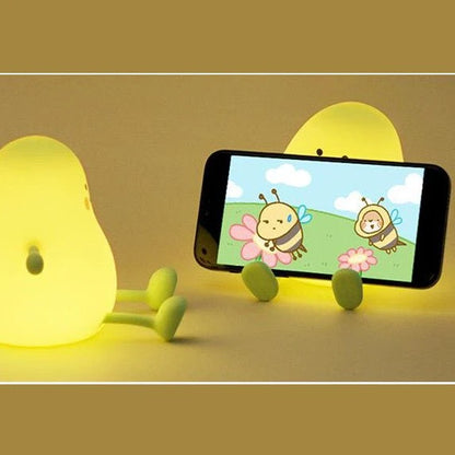 Veilleuse LumiBuddy Mangue utilisée comme support smartphone lumière jaune fond doré — Mon Univers - Mes Lumières
