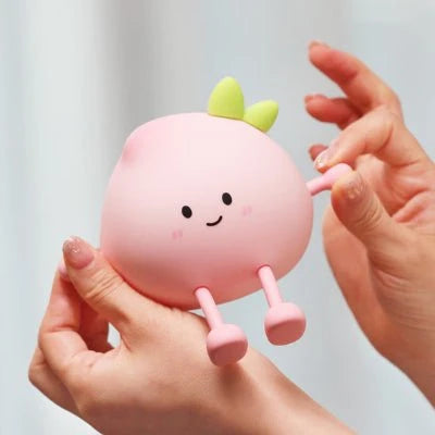 Veilleuse LumiBuddy Pêche silicone rose tenue dans les mains vue rapprochée — Mon Univers - Mes Lumières